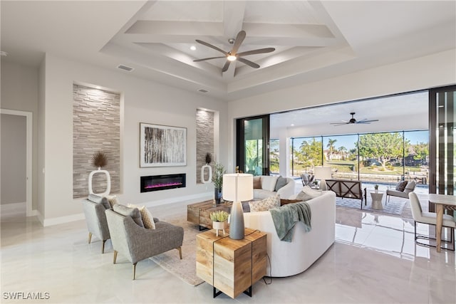 living room featuring ceiling fan, a tray ceiling, and a wealth of natural light