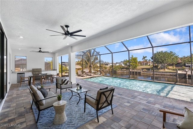 view of pool with a water view, outdoor lounge area, a lanai, ceiling fan, and a patio