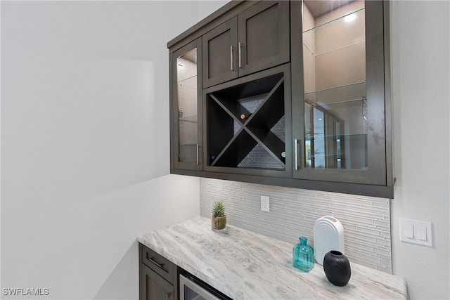 bar featuring light stone counters, dark brown cabinetry, and decorative backsplash