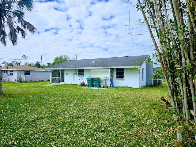 rear view of house with cooling unit and a lawn