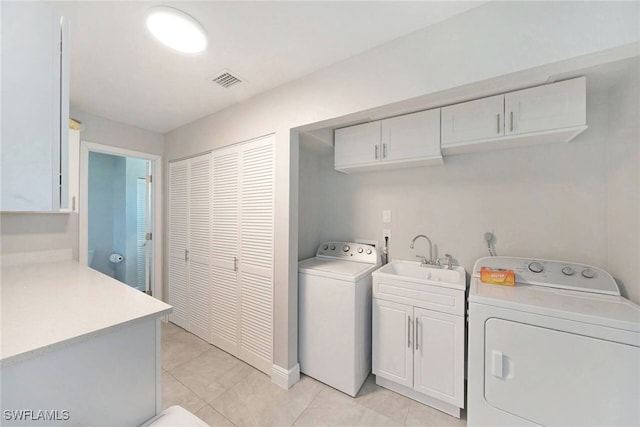 laundry room with washing machine and clothes dryer, sink, light tile patterned flooring, and cabinets