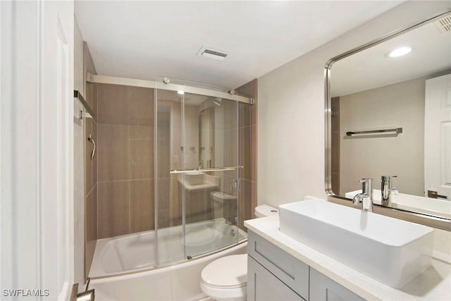 full bathroom with vanity, enclosed tub / shower combo, and toilet