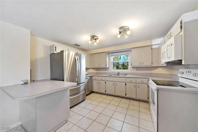 kitchen with cream cabinets, sink, light tile patterned floors, appliances with stainless steel finishes, and kitchen peninsula