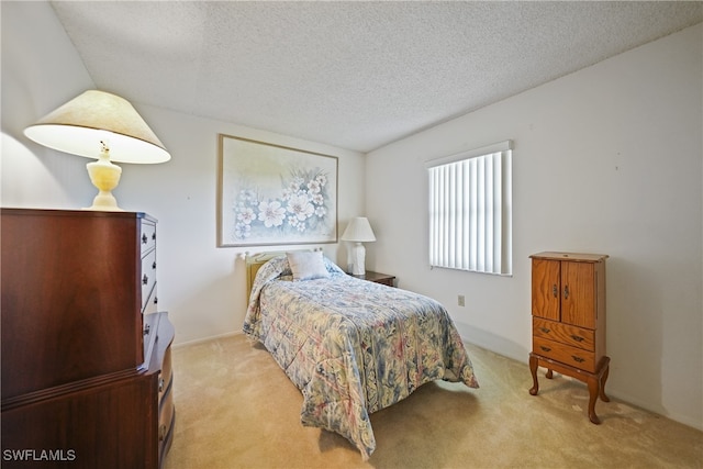 bedroom with light colored carpet and a textured ceiling