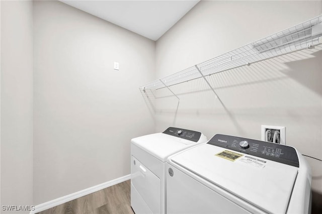 clothes washing area with washing machine and clothes dryer, baseboards, light wood-style floors, and laundry area