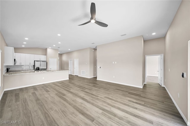 unfurnished living room with ceiling fan, light hardwood / wood-style flooring, and vaulted ceiling