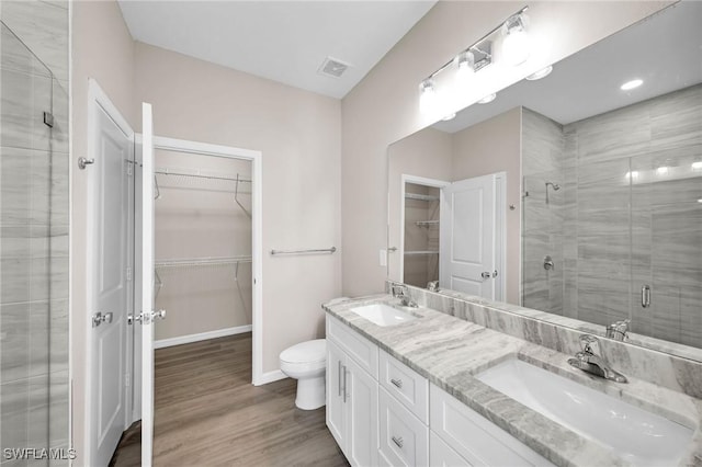 bathroom with a sink, visible vents, wood finished floors, and a shower stall