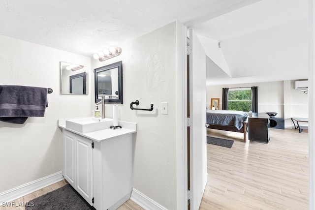 bathroom with a wall mounted air conditioner, vanity, lofted ceiling, and hardwood / wood-style flooring