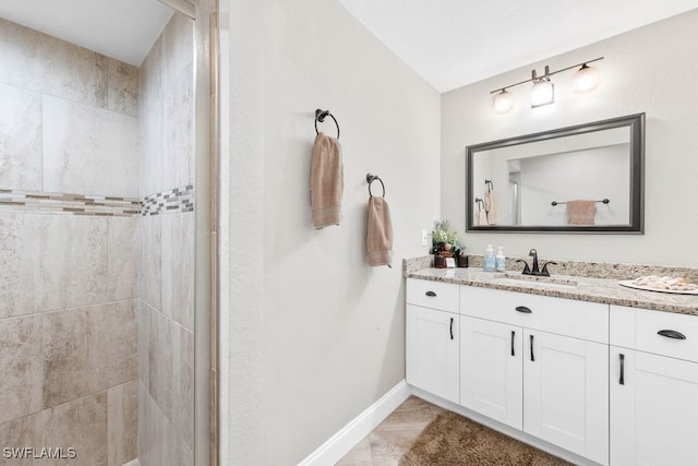 bathroom with tiled shower and vanity