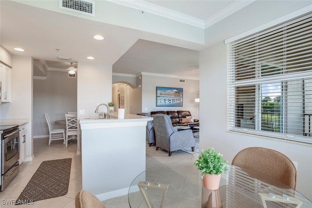 kitchen featuring stainless steel range with electric cooktop, white cabinetry, light tile patterned floors, ornamental molding, and ceiling fan