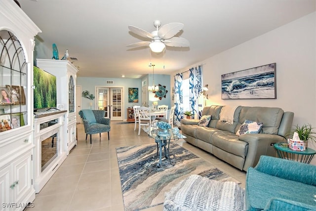 tiled living room featuring french doors and ceiling fan with notable chandelier