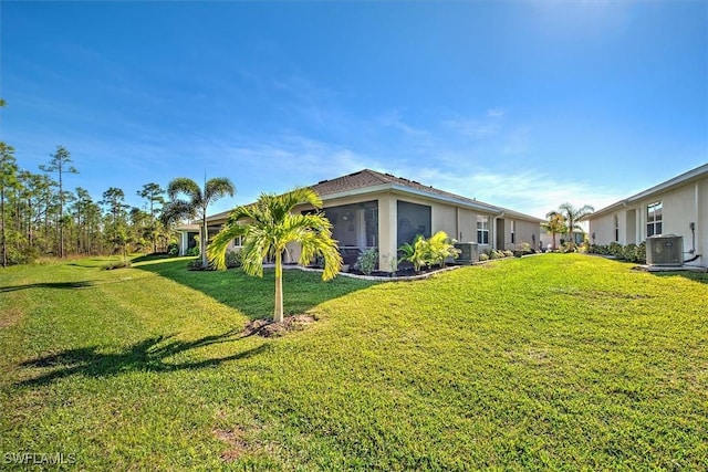 view of side of home with a sunroom, a yard, and central AC unit