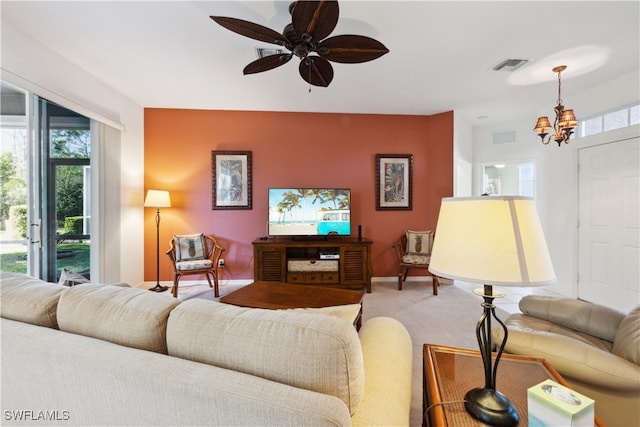 carpeted living room featuring ceiling fan with notable chandelier