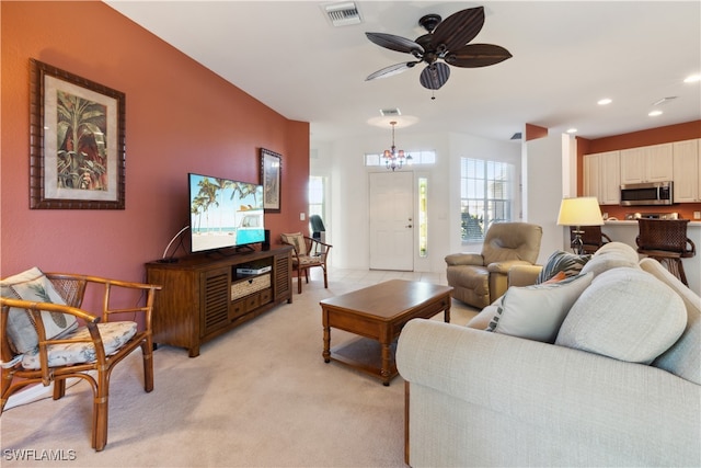 carpeted living room with ceiling fan with notable chandelier