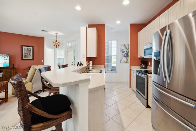 kitchen featuring sink, kitchen peninsula, pendant lighting, a kitchen bar, and appliances with stainless steel finishes