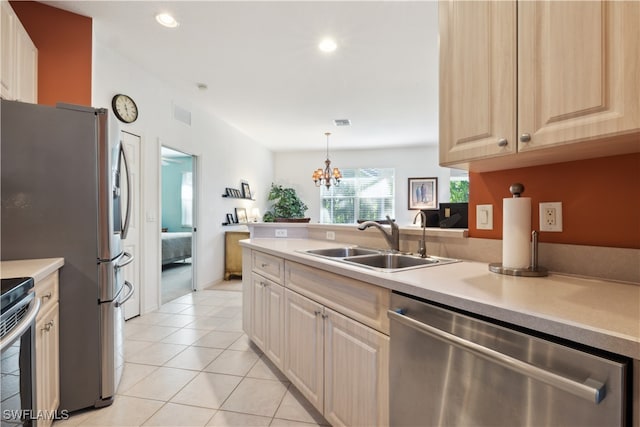 kitchen featuring stainless steel appliances, sink, pendant lighting, light brown cabinets, and an inviting chandelier