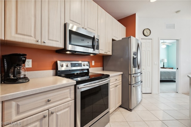 kitchen with light brown cabinetry, stainless steel appliances, ceiling fan, and light tile patterned flooring