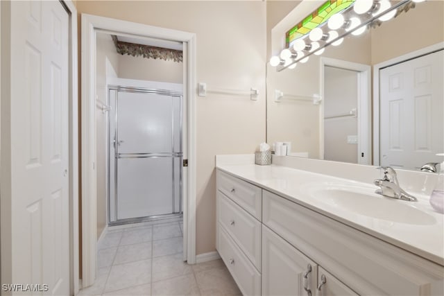 bathroom with tile patterned flooring, vanity, and a shower with door