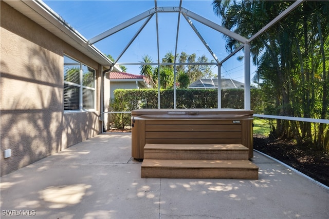 view of patio / terrace with glass enclosure and a hot tub