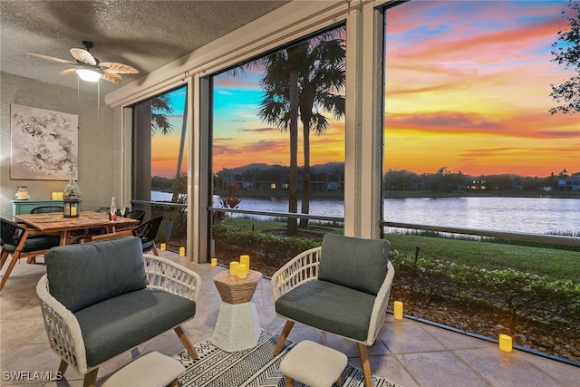 sunroom / solarium with a water view, ceiling fan, and a healthy amount of sunlight