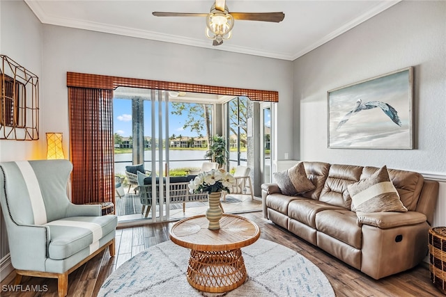 living room with ceiling fan, a water view, wood-type flooring, and ornamental molding