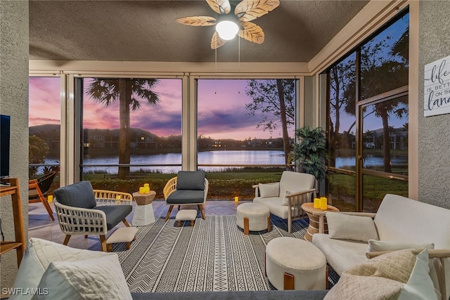 sunroom featuring ceiling fan, a water view, and a wealth of natural light