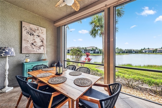 tiled dining area featuring ceiling fan, a water view, and a textured ceiling