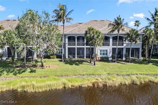 back of property with a water view and a yard