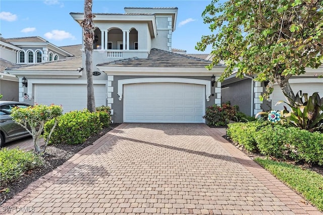 9229 Museo Cir Unit 102, Naples, FL 34114 - view of front of house with a balcony, stucco siding, decorative driveway, and an attached garage