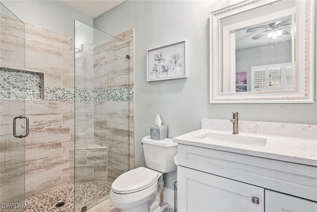 bathroom with an enclosed shower, vanity, toilet, and ceiling fan