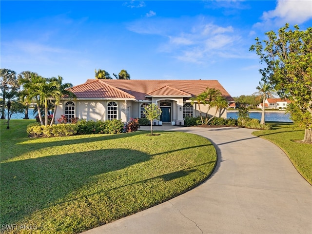 mediterranean / spanish home featuring a front yard and a water view