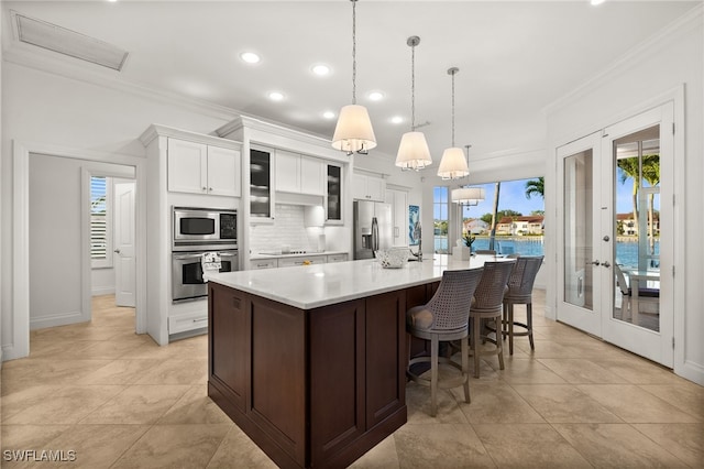 kitchen with appliances with stainless steel finishes, french doors, ornamental molding, decorative light fixtures, and white cabinets