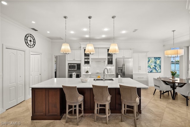 kitchen featuring a breakfast bar, sink, decorative light fixtures, appliances with stainless steel finishes, and a large island