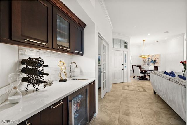 kitchen featuring decorative backsplash, dark brown cabinetry, sink, pendant lighting, and wine cooler