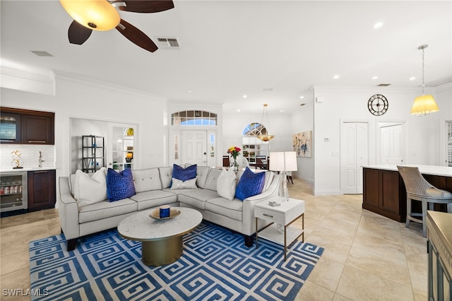 living room with ceiling fan, light tile patterned floors, crown molding, and beverage cooler