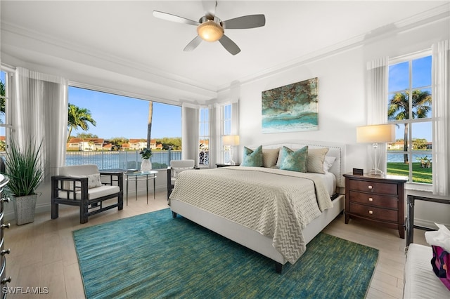 bedroom featuring wood-type flooring, a water view, ceiling fan, and crown molding