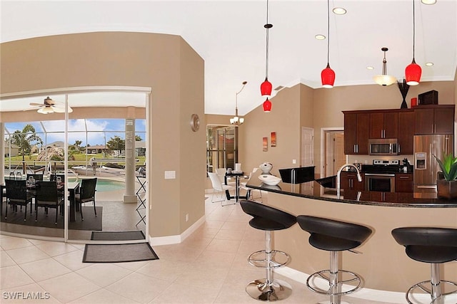 kitchen with dark brown cabinetry, sink, decorative light fixtures, light tile patterned flooring, and appliances with stainless steel finishes