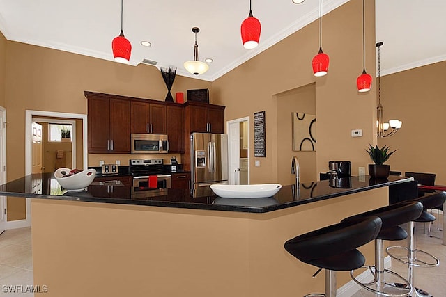 kitchen with dark brown cabinetry, a center island with sink, pendant lighting, and appliances with stainless steel finishes