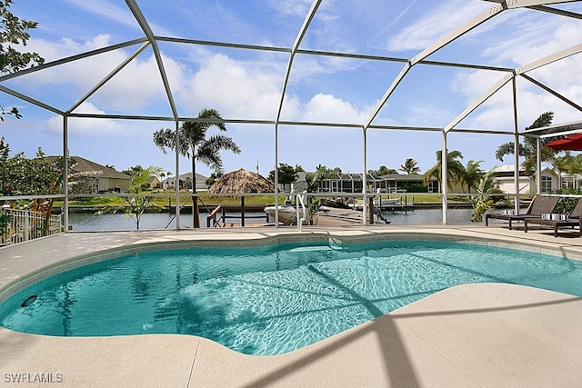 view of pool with glass enclosure, a patio area, and a water view