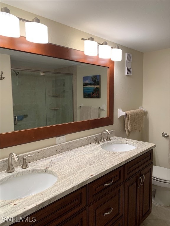 bathroom with tile patterned floors, vanity, toilet, and a shower with door