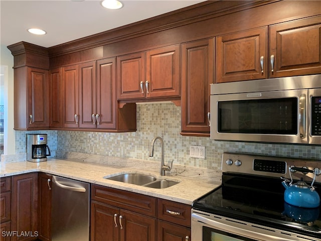 kitchen with tasteful backsplash, light stone counters, sink, and appliances with stainless steel finishes