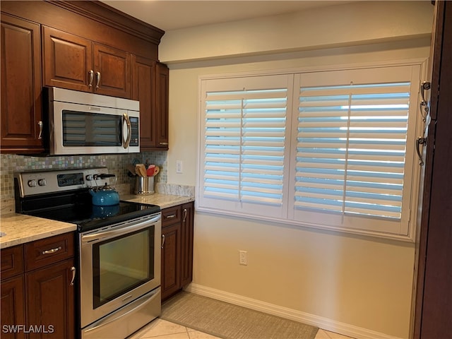 kitchen featuring light stone countertops, appliances with stainless steel finishes, tasteful backsplash, dark brown cabinets, and light tile patterned flooring