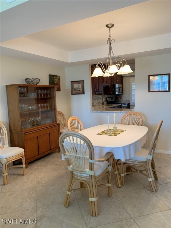 dining room with a chandelier, light tile patterned floors, and a tray ceiling