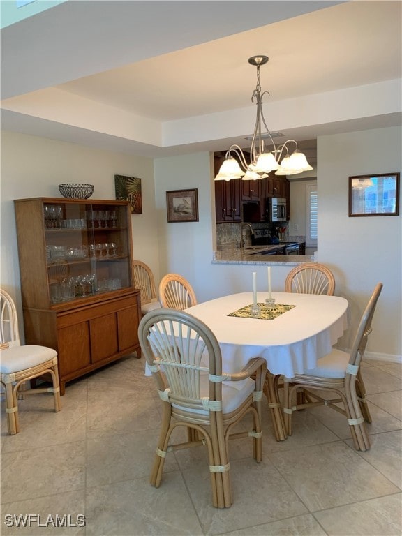 200 Periwinkle Way Unit 332, Sanibel, FL 33957 - dining space featuring a chandelier, light tile patterned floors, a raised ceiling, and baseboards