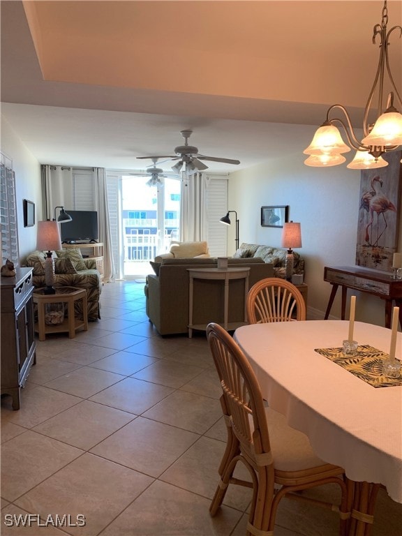 tiled dining room with ceiling fan with notable chandelier