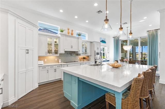 kitchen featuring decorative light fixtures, white cabinetry, a breakfast bar, and a large island with sink