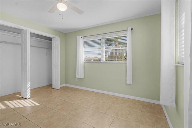 unfurnished bedroom with light tile patterned floors, two closets, and ceiling fan