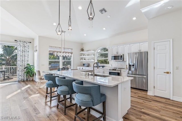 kitchen with a healthy amount of sunlight, white cabinetry, hanging light fixtures, and appliances with stainless steel finishes