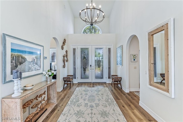 entryway with french doors, high vaulted ceiling, a chandelier, and light hardwood / wood-style flooring