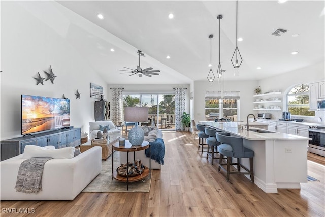 living room featuring ceiling fan, sink, high vaulted ceiling, and light hardwood / wood-style floors